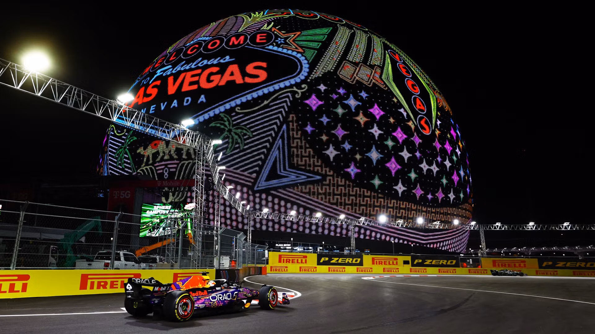 A Formula 1 car on the night circuit passing the illuminated Sphere in Las Vegas