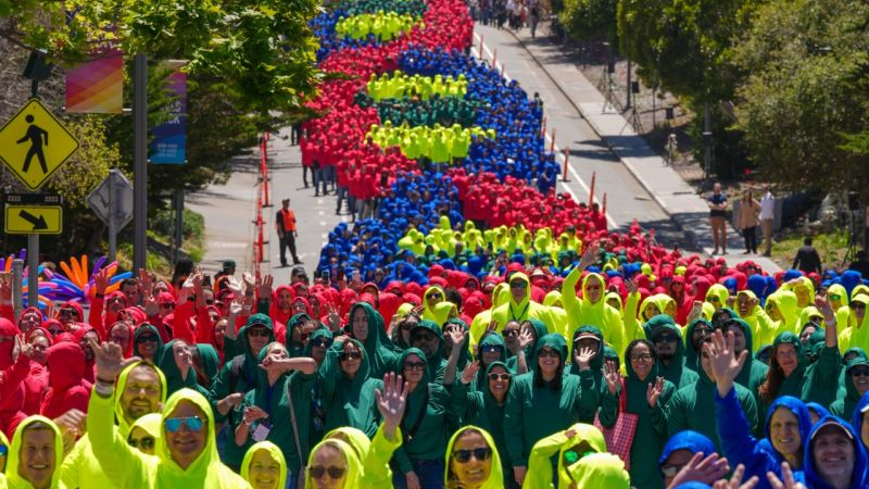 The completed human DNA helix curving down DNA Way as participants in red, green, yellow and blue hoodies wave