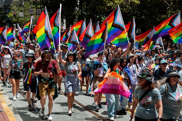 Marchers carrying Progress Pride flags down Market Street