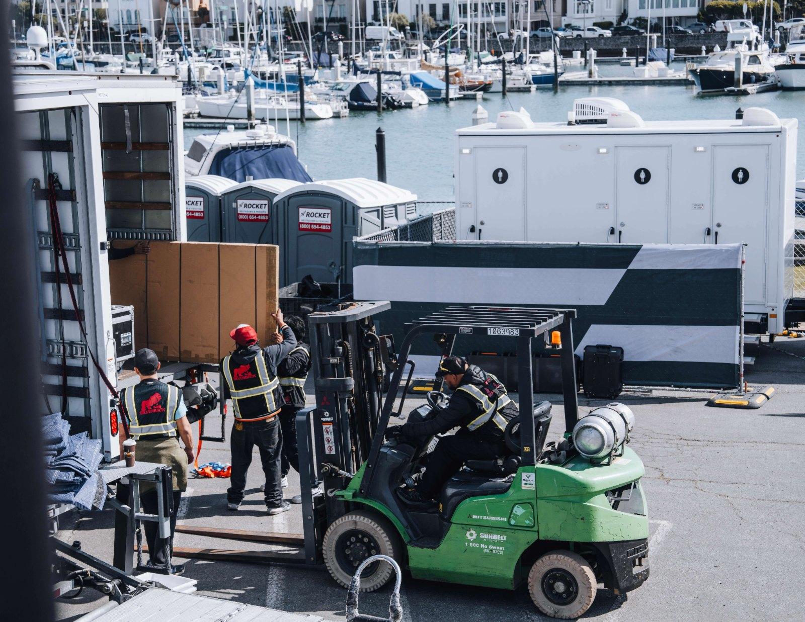 Silverback crew unloading a truck by forklift at the marina during SailGP load-in