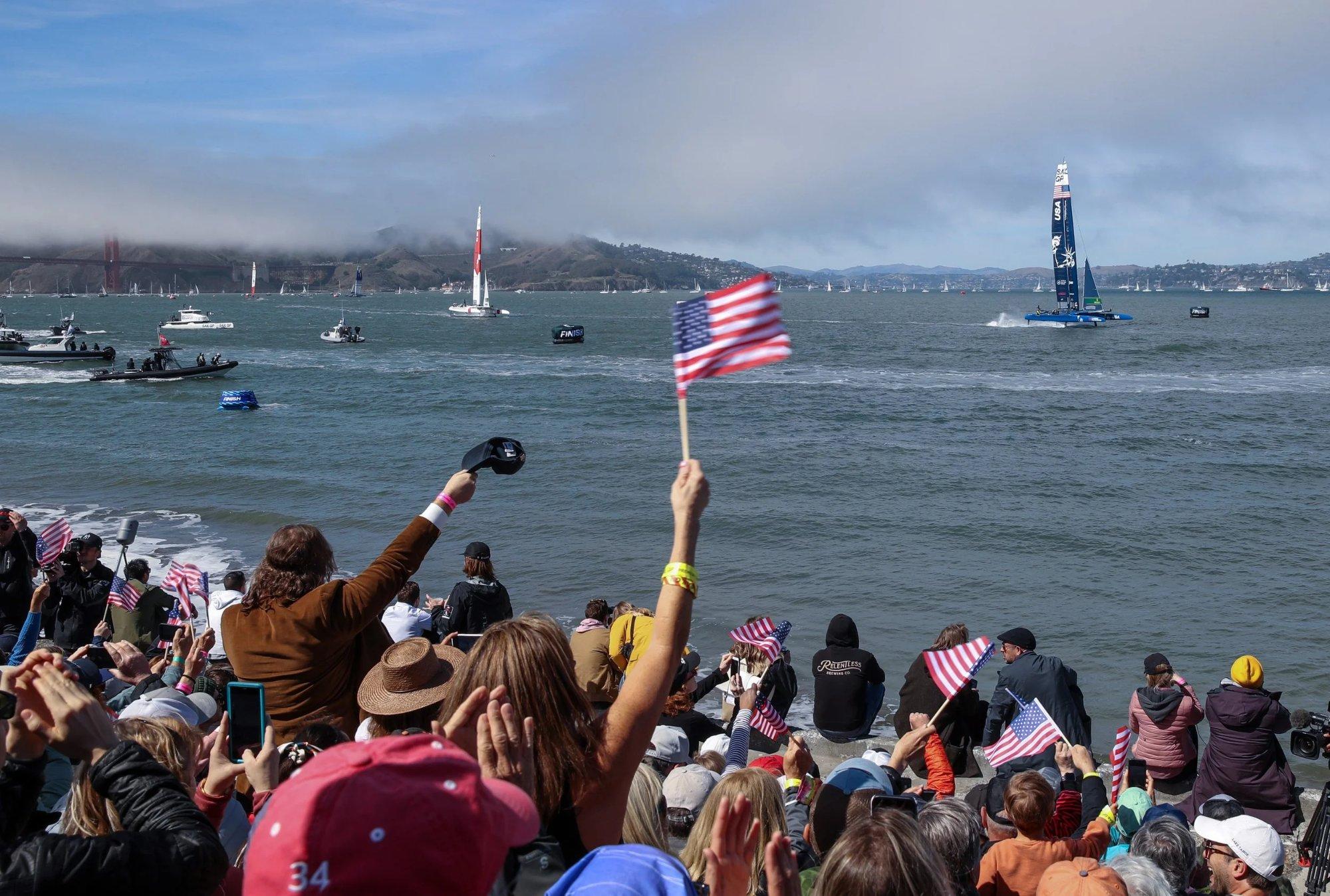 Spectators watching SailGP from the shoreline as the F50s cross the finish