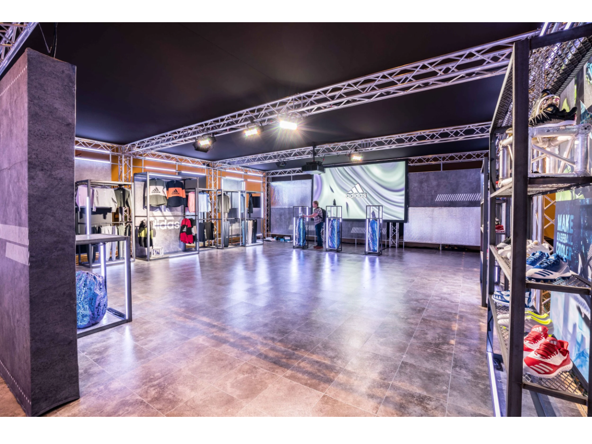 Interior of the Adidas Space Race activation with lit truss, product displays and screens