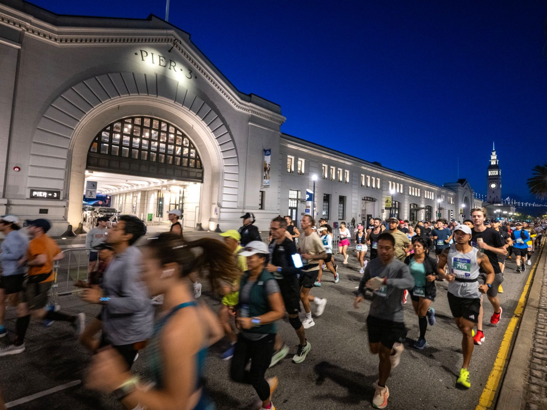 Runners passing Pier 3 on the Embarcadero at dawn during the San Francisco Marathon